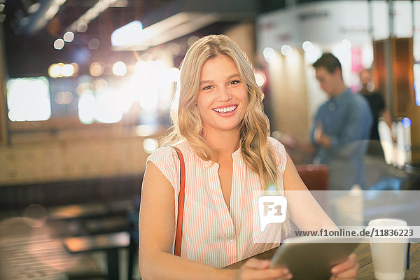 Portrait smiling young woman using digital tablet at cafe