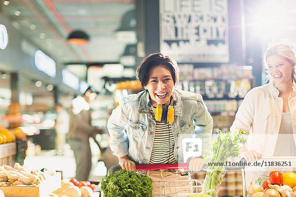 Porträt verspielte junge Frau mit Einkaufswagen Lebensmittelgeschäft Einkaufen im Markt