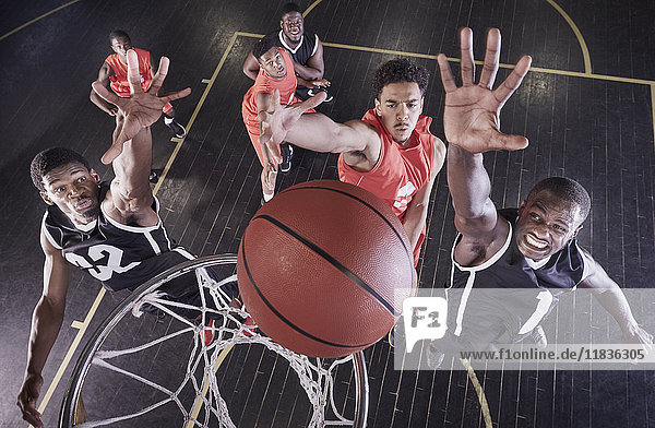 Overhead-Ansicht junge männliche Basketballspieler springen zum Rebound Basketball am Netz auf dem Basketballplatz.