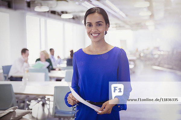 Portrait lächelnde Geschäftsfrau mit Papierkram im Büro