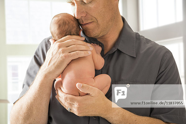 Vater umarmt neugeborenen Sohn (0-1 Monat)