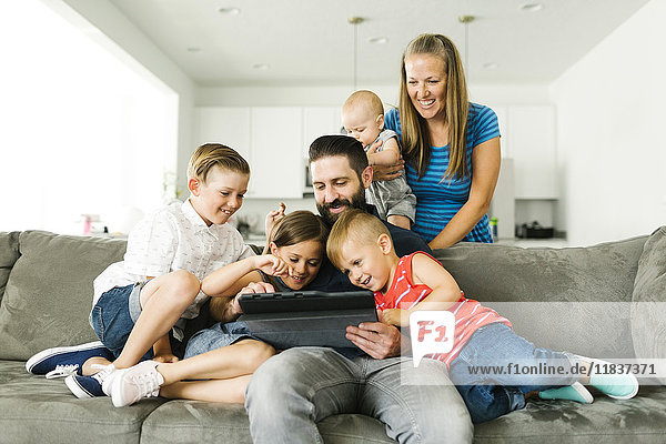 Family with four children (6-11 months  2-3  6-7) using digital tablet