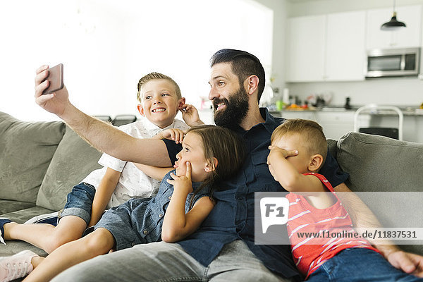 Vater mit seinen drei Kindern (2-3  6-7) macht Selfie mit Smartphone