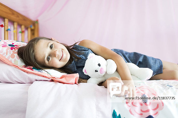 Porträt eines Mädchens (6-7) auf dem Bett liegend