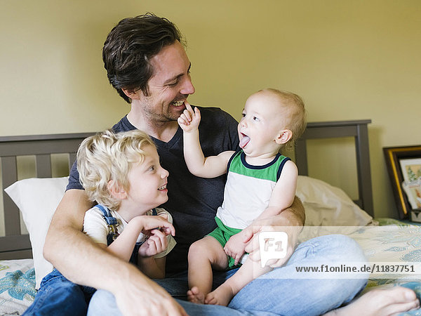 Vater spielt mit Söhnen (12-17 Monate  4-5) im Schlafzimmer