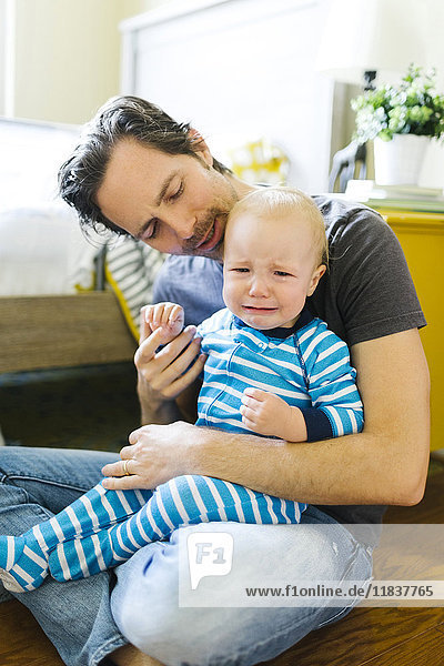 Vater umarmt traurigen Sohn (12-17 Monate)