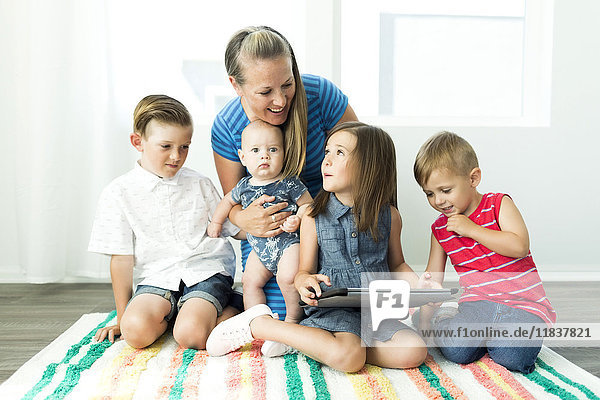 Mother with children (6-11 months  2-3  6-7) using digital tablet at home