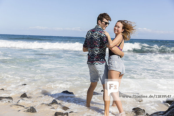 Lächelndes  sich umarmendes Paar am windigen Strand