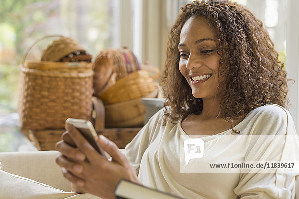 Afroamerikanische Frau  die eine SMS auf ihrem Handy schreibt