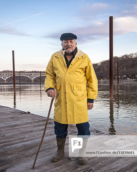 Älterer kaukasischer Fischer auf dem Steg stehend