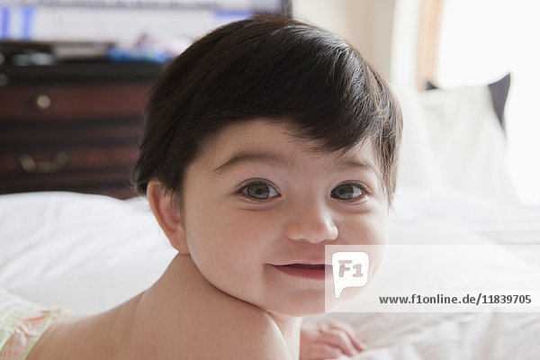 Portrait of smiling Hispanic baby boy laying on bed