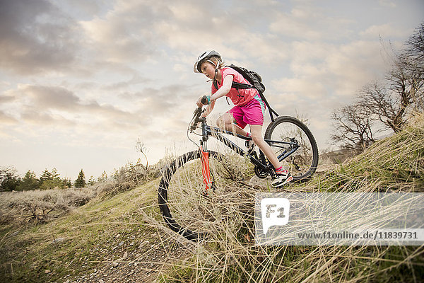 Caucasian girl riding bicycle on hill