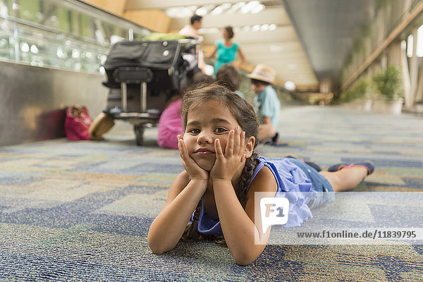 Gelangweiltes Mädchen liegt auf dem Boden eines Flughafens