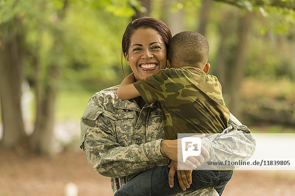 African American soldier mother carrying and hugging son