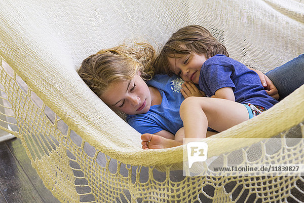 Caucasian brother and sister cuddling in hammock