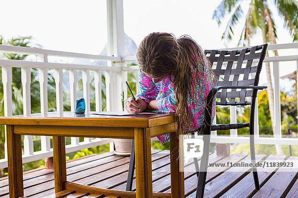 Kaukasisches Mädchen sitzt auf dem Balkon und zeichnet auf Papier