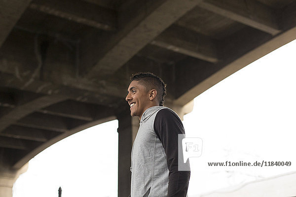 Lächelnder Mixed-Race-Mann unter Brücke stehend