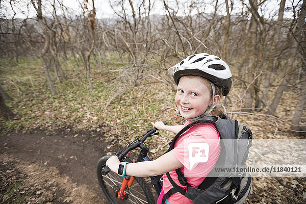Caucasian girl riding bicycle on forest path