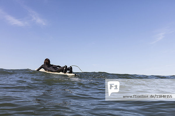 Kaukasischer Mann paddelt auf einem Surfbrett