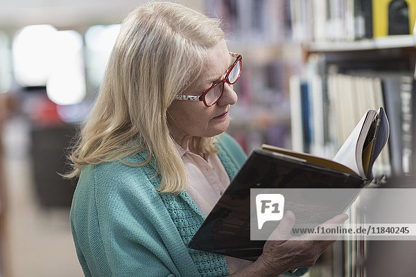 Kaukasische Frau liest ein Buch in der Bibliothek