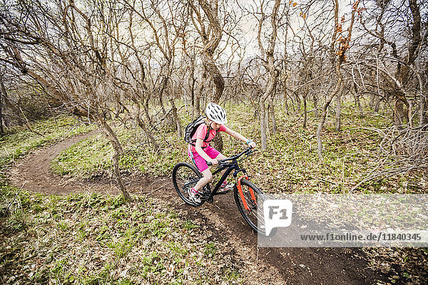 Kaukasisches Mädchen fährt Fahrrad auf einem Waldweg