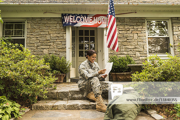 Lächelnder afroamerikanischer Soldat sitzt auf der Treppe und liest einen Brief
