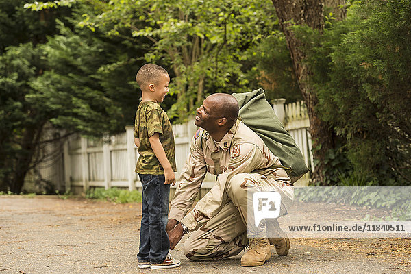 Afroamerikanischer Soldat bindet Schnürsenkel für Sohn