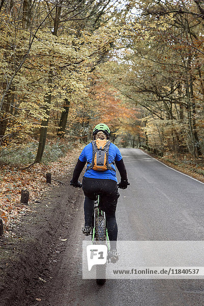 Caucasian woman riding bicycle on forest road