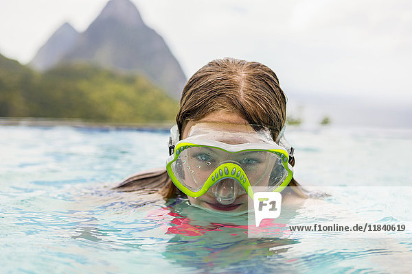 Caucasian girl wearing snorkel mask in swimming pool
