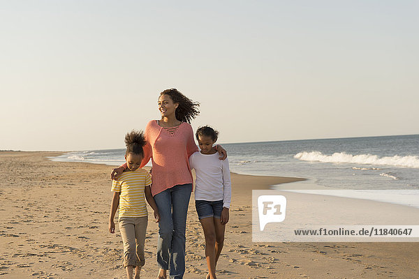 Mother and daughters walking on beach