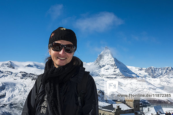 Eine Touristin posiert mit dem Hotel und Observatorium Gornergrat Kulm und dem Matterhorn im Hintergrund; Schweiz'.