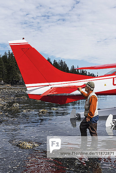 Man standing next to a Cessna 206 float plane in Hobo Bay  Port Wells  Prince William Sound  Southcentral Alaska  USA