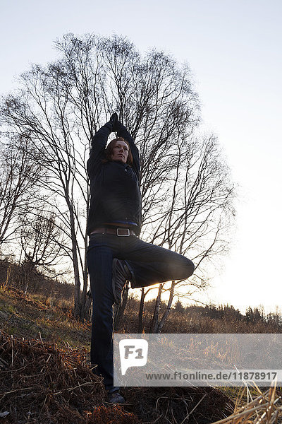 Eine Frau macht Yoga an einem Berghang im Herbst; Alaska  Vereinigte Staaten von Amerika'.