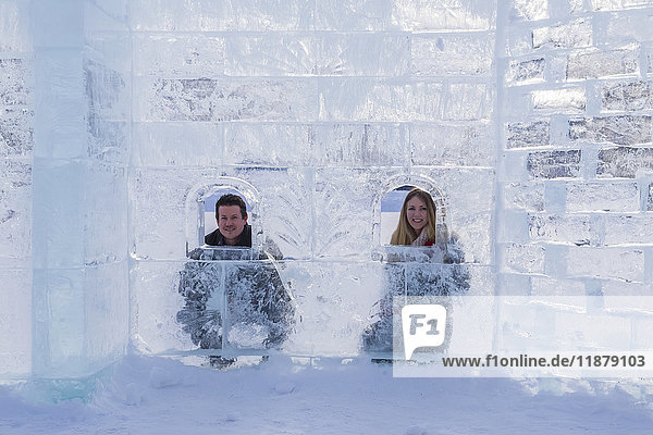 Ein junges Touristenpaar posiert in einer Eisburg  die auf dem Eis des Lake Louise im Banff National Park gebaut wurde; Lake Louise  Alberta  Kanada'.
