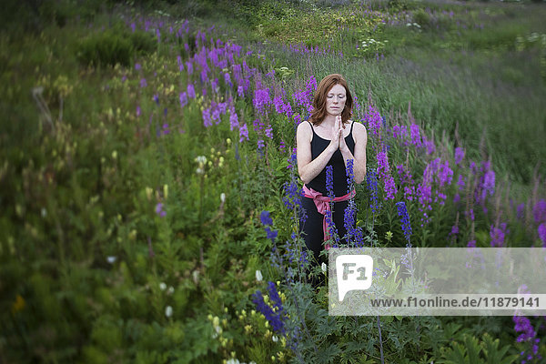 'Eine Frau macht Yoga auf einer Wiese mit Wildblumen; Homer  Alaska  Vereinigte Staaten von Amerika'.