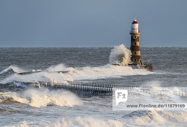 Waves splashing against Roker lighthouse at the end of a pier; Sunderland  Tyne and Wear  England