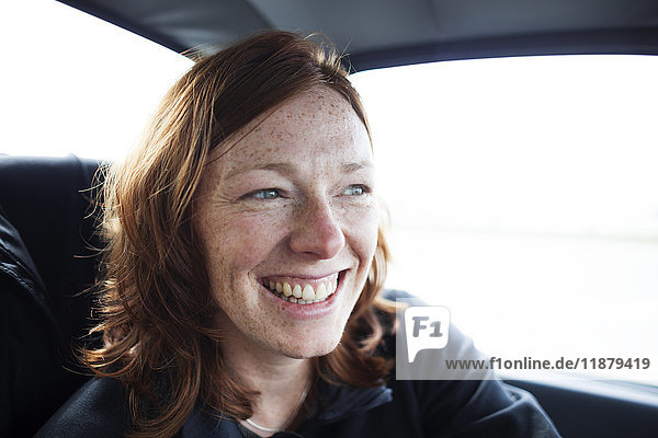 'A woman with red hair and freckles smiling while riding in a car; Alaska  United States of America'