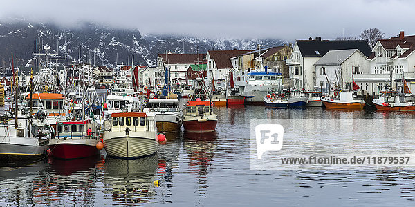 Boote im Hafen und Gebäude am Ufer mit tief hängenden Wolken; Lofoton Inseln  Nordland  Norwegen'.
