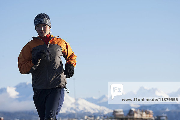 Eine junge Frau läuft vor einer schneebedeckten Bergkette im Hintergrund; Homer  Alaska  Vereinigte Staaten von Amerika'.