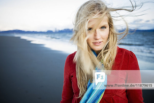 Porträt einer jungen Frau  die am Strand steht und ihr langes blondes Haar im Wind wehen lässt; Homer  Alaska  Vereinigte Staaten von Amerika