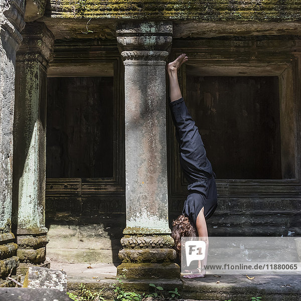 Eine Frau macht einen Handstand im Ta-Prohm-Tempel; Krong Siem Reap  Provinz Siem Reap  Kambodscha'.