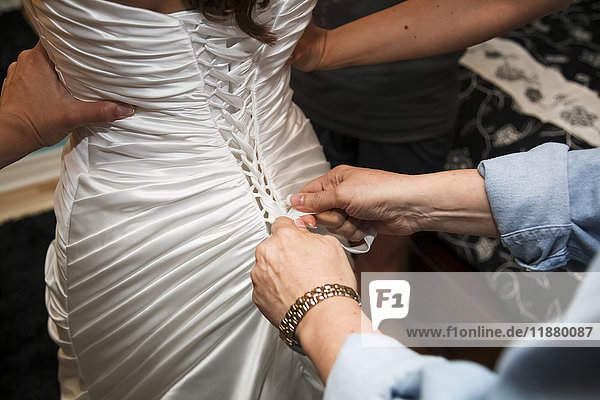 Eine Frau hilft einer Braut an ihrem Hochzeitstag beim Ankleiden; Ontario  Kanada'.