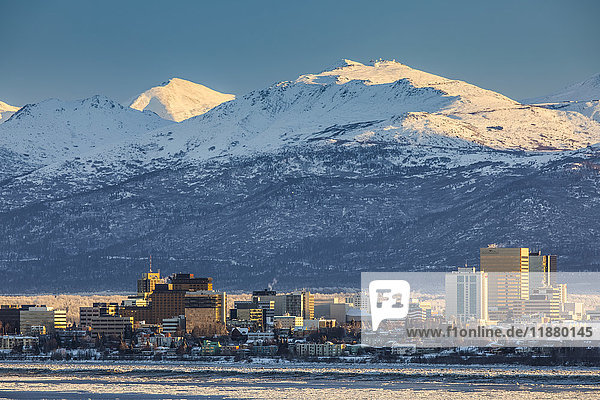 'View of downtown Anchorage in winter and the snow-capped Chugach Mountains beyond seen from Point MacKenzie  the skies in the background clear and bright  sea ice covering Cook Inlet in the foreground  South-central Alaska; Anchorage  Alaska  United States of America'