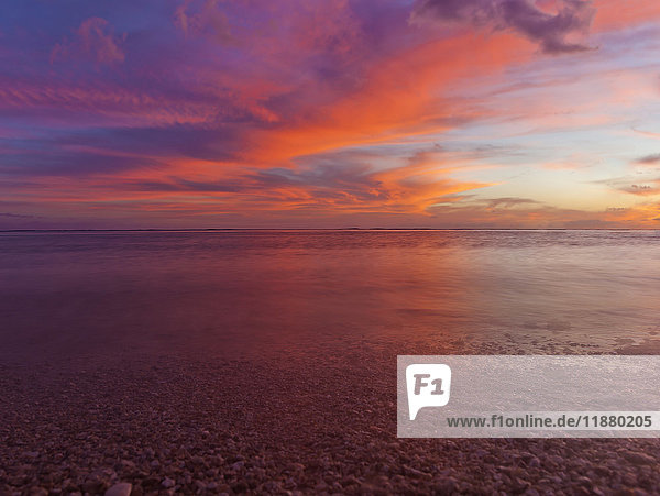 Eine dramatische Strandlandschaft mit den Farben des Himmels und des Meeres bei Sonnenuntergang  aufgenommen mit Langzeitbelichtung; Honolulu  Oahu  Hawaii  Vereinigte Staaten von Amerika'.