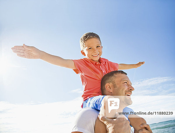 'A boy piggybacking on his dad flying like an airplane with his arms; Honolulu  Oahu  Hawaii  United States of America'