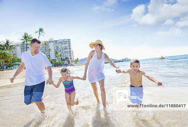 Eine vierköpfige Familie genießt einen Sommerurlaub am Waikiki Beach; Honolulu  Oahu  Hawaii  Vereinigte Staaten von Amerika'.