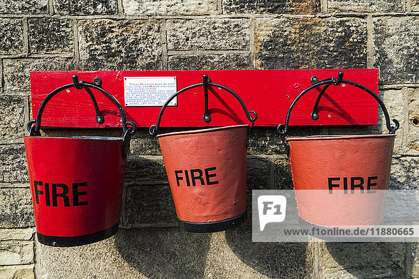 'Three red pails labeled fire hanging on a wall; Yorkshire  England'