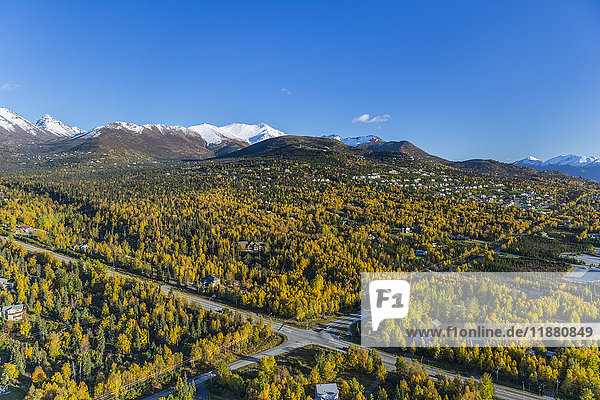'Aerial view of the hillside neighbourhood homes in Anchorage  snow covering the peaks of the Chugach Mountains in the background  autumn coloured trees filling the city  South-central Alaska; Alaska  United States of America'