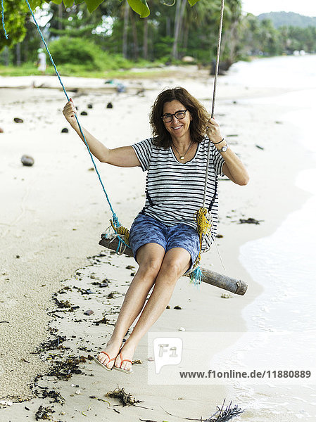 'A woman sits on a tree swing on the beach along the Gulf of Thailand; Ko Samui  Chang Wat Surat Thani  Thailand '