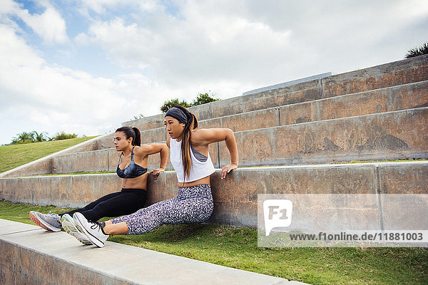 Zwei junge Frauen trainieren im Freien und machen Liegestützen auf Stufen South Point Park Miami Beach Florida USA